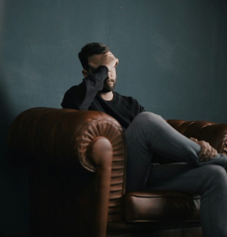 You don't have to carry this alone Man sitting cross-legged with his head in his hand, therapy for men in Exeter & Exmouth